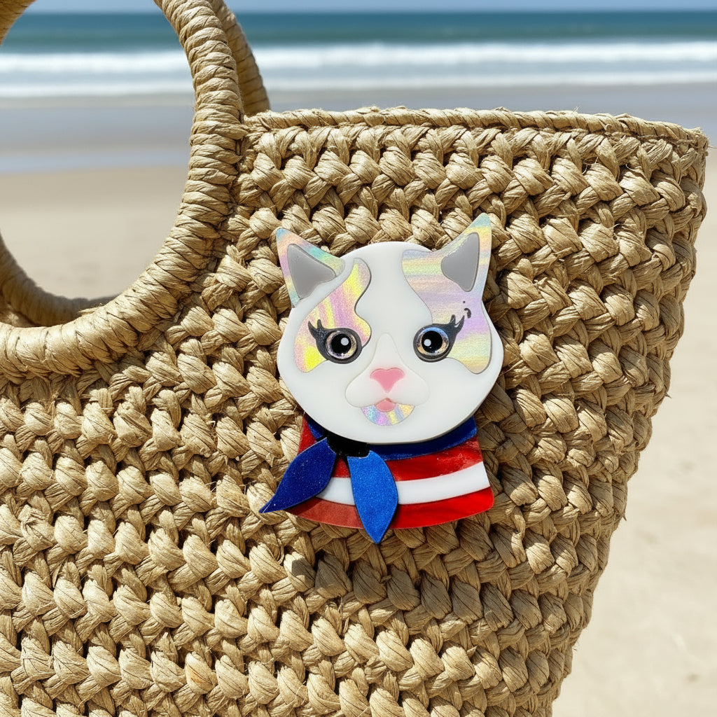 Cat-shaped brooch with a colorful design pinned on a straw beach bag