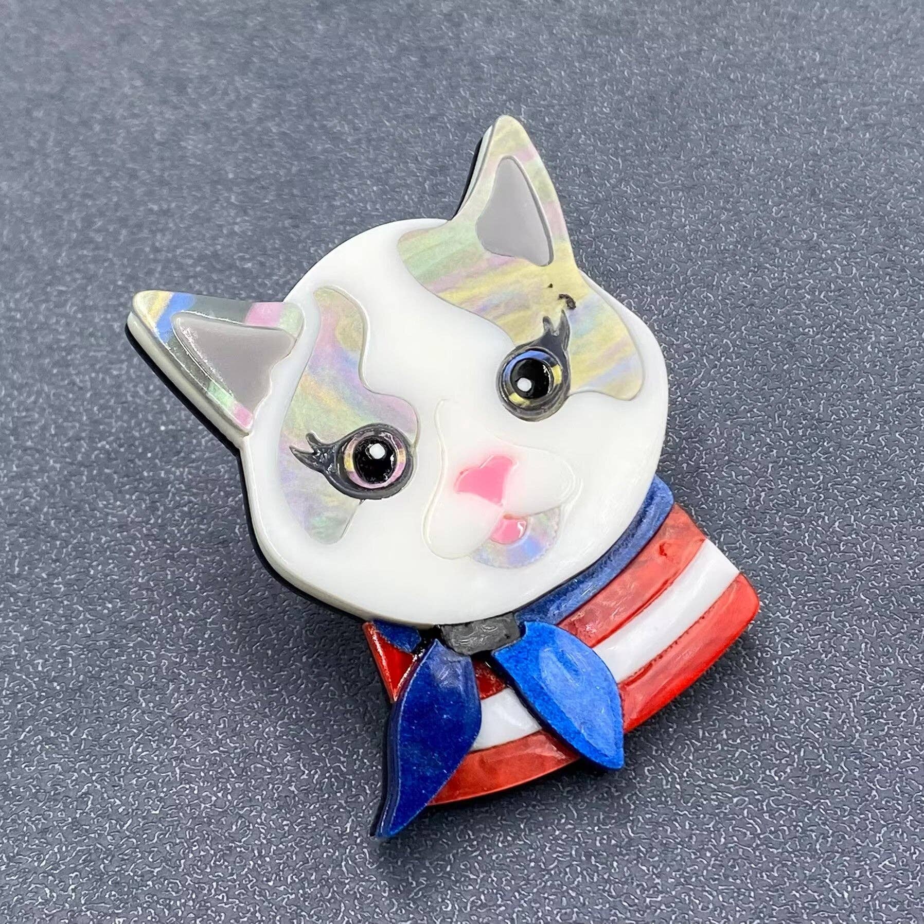 Cat-shaped brooch with a colorful design on a gray background