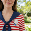 Cat-shaped brooch with a colorful design pinned on a stripped shirt