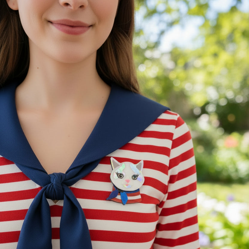 Cat-shaped brooch with a colorful design pinned on a stripped shirt
