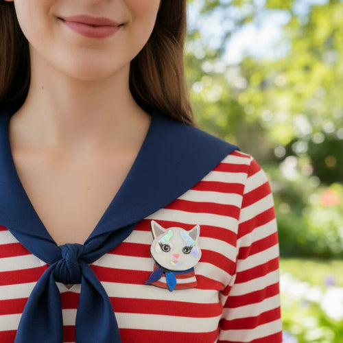 Cat-shaped brooch with a colorful design pinned on a stripped shirt