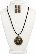 A black cord necklace with an antique bronze sun pendant, displayed on a cream-colored bust alongside matching mix-metal earrings.
