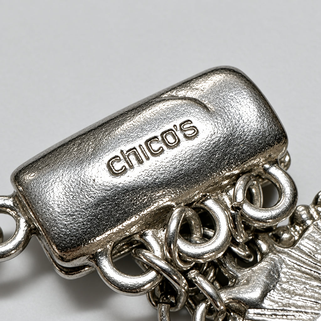 Close-up view of a silver-toned metal bracelet clasp with Chico's hallmark, against a neutral light background.