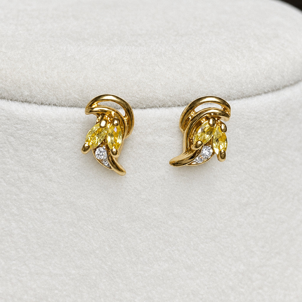 A gold jewelry set displayed on a white velvet mannequin bust, featuring a delicate chain necklace and matching curved hoop earrings with small clear stones.