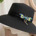 Colorful dragonfly brooch with golden accents pinned on a black hat