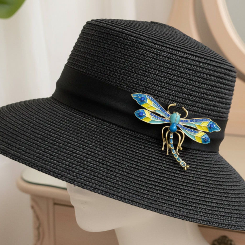 Colorful dragonfly brooch with golden accents pinned on a black hat