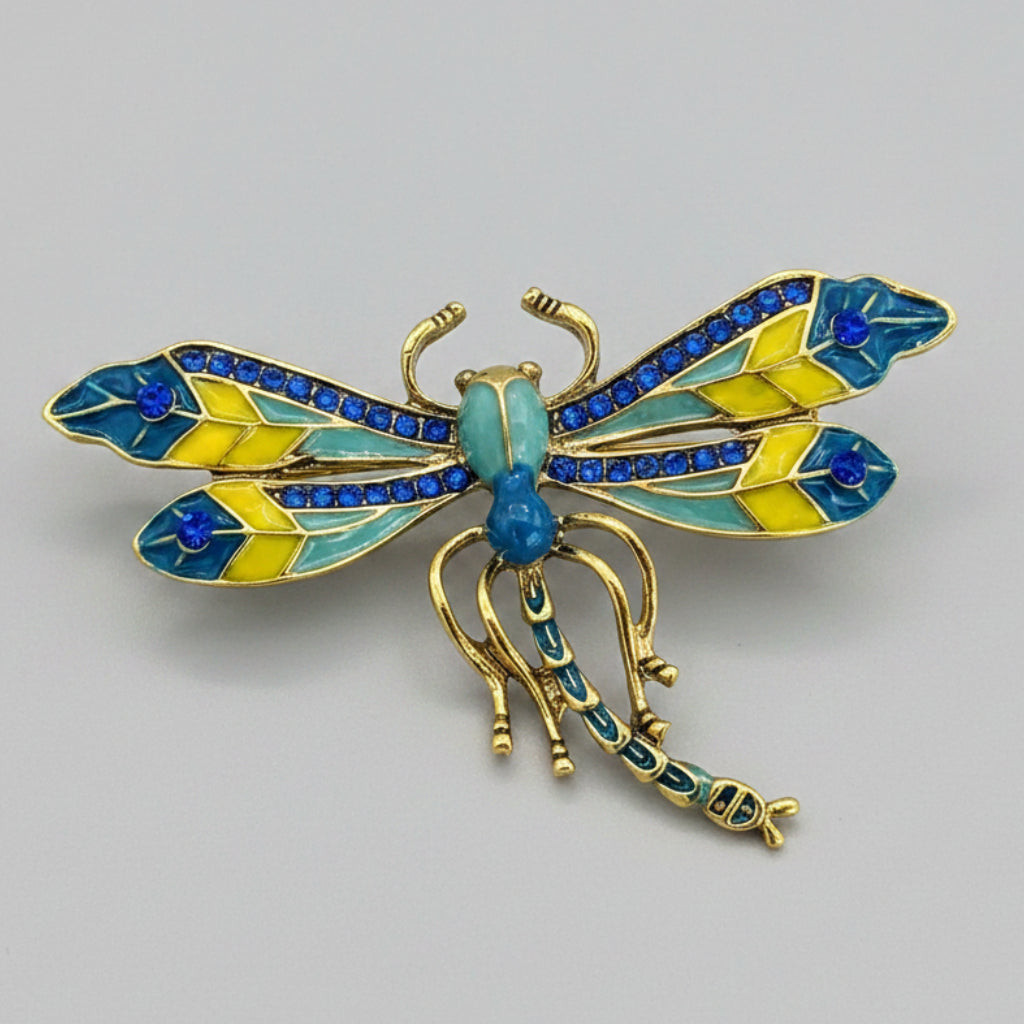 Colorful dragonfly brooch with golden accents on a gray background