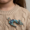 Decorative cat-shaped brooch with colorful gemstones pinned on a beige sweater