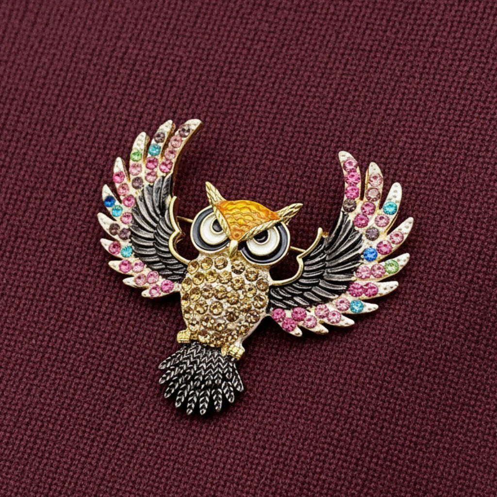 Decorative owl brooch with gemstones on a maroon sweater