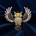 Decorative owl brooch with colorful gemstones on a blue background