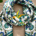 Colorful bird-shaped brooch pinned on a paisley scarf