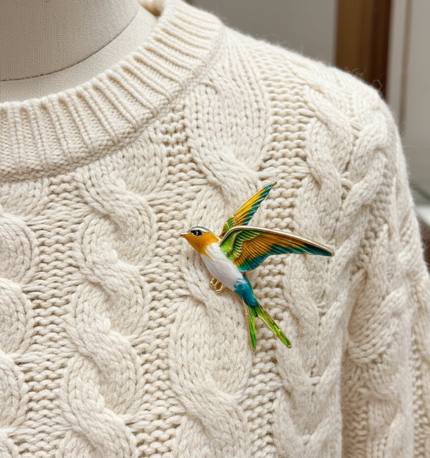 Colorful bird-shaped brooch pinned on a white sweater