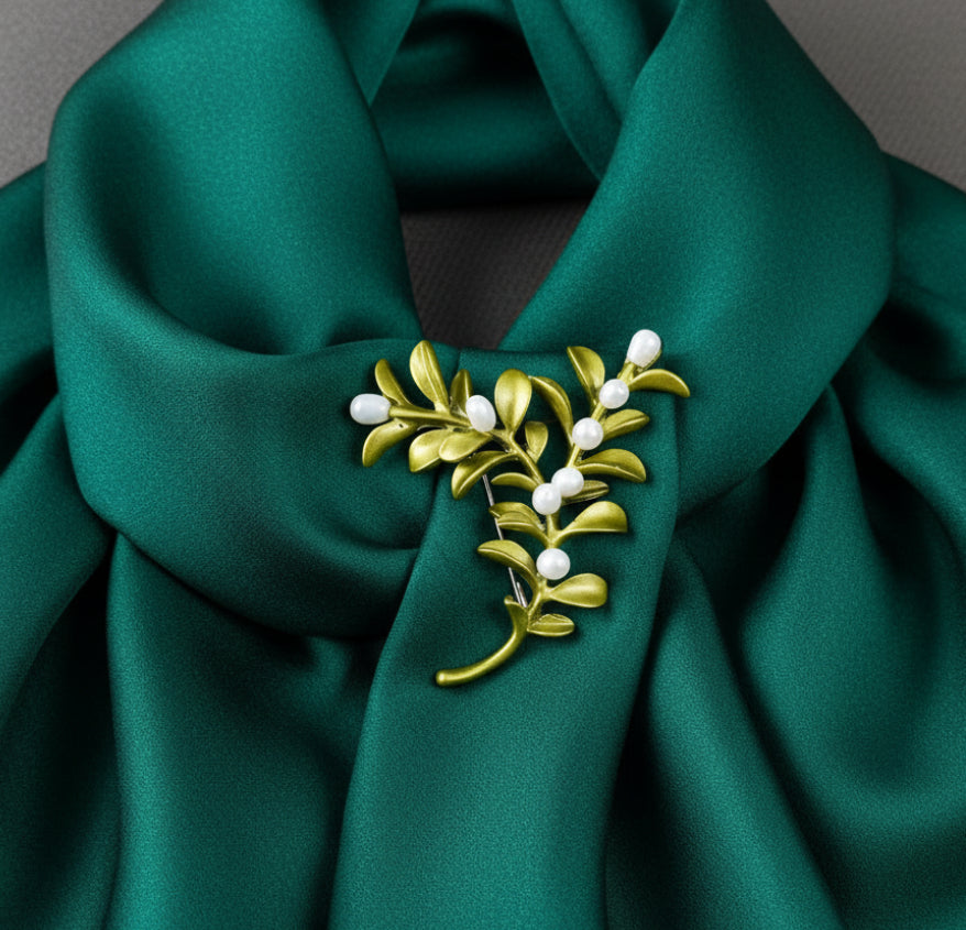 Boxwood plant brooch with green leaves and white berries on a gray background