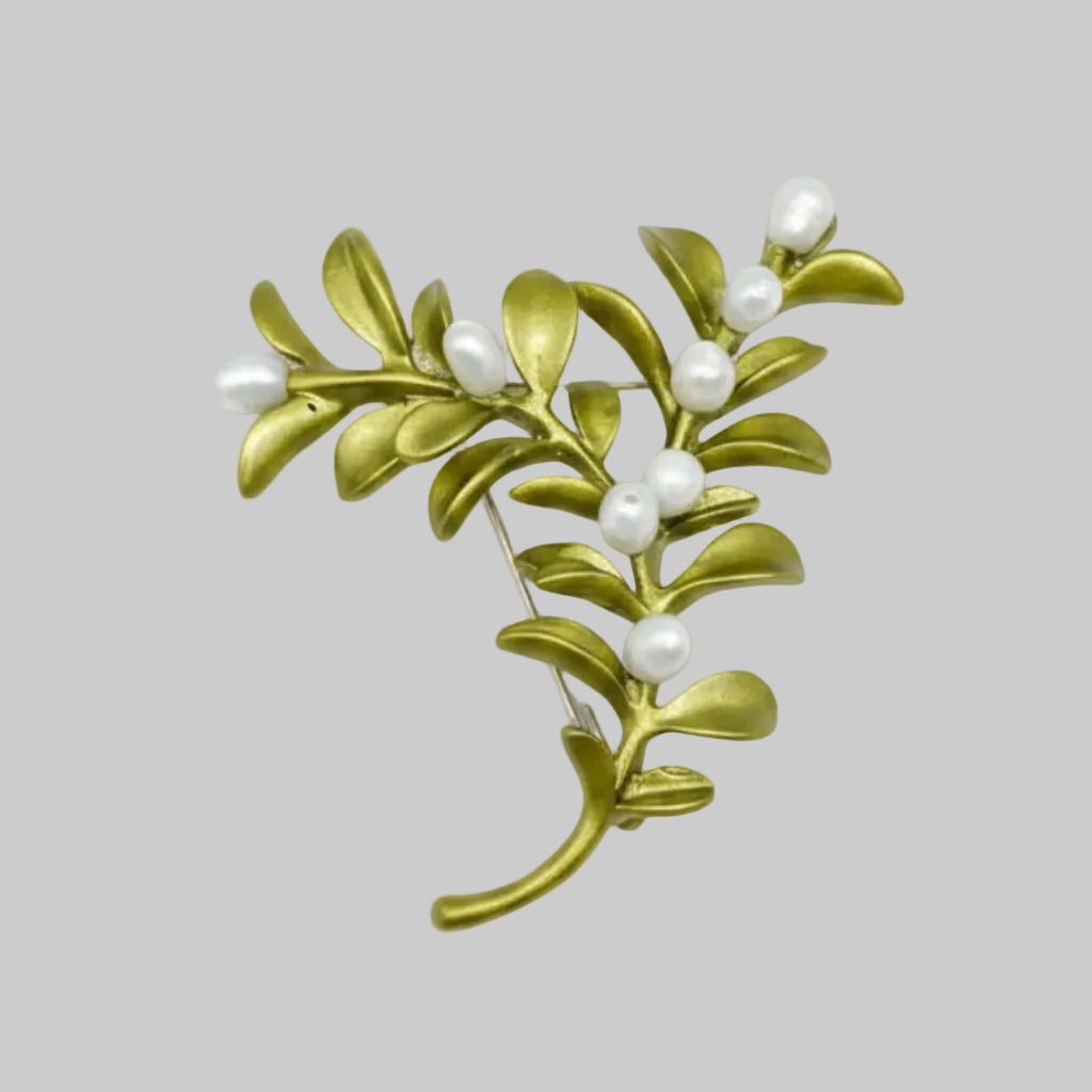 Boxwood plant brooch with green leaves and white berries on a gray background
