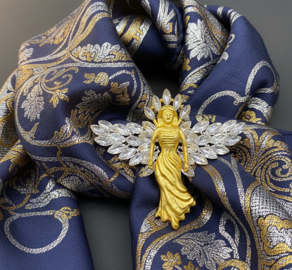 Gold angel brooch with crystal wings pinned on a blue floral scarf