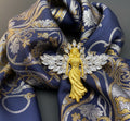 Gold angel brooch with crystal wings pinned on a blue floral scarf