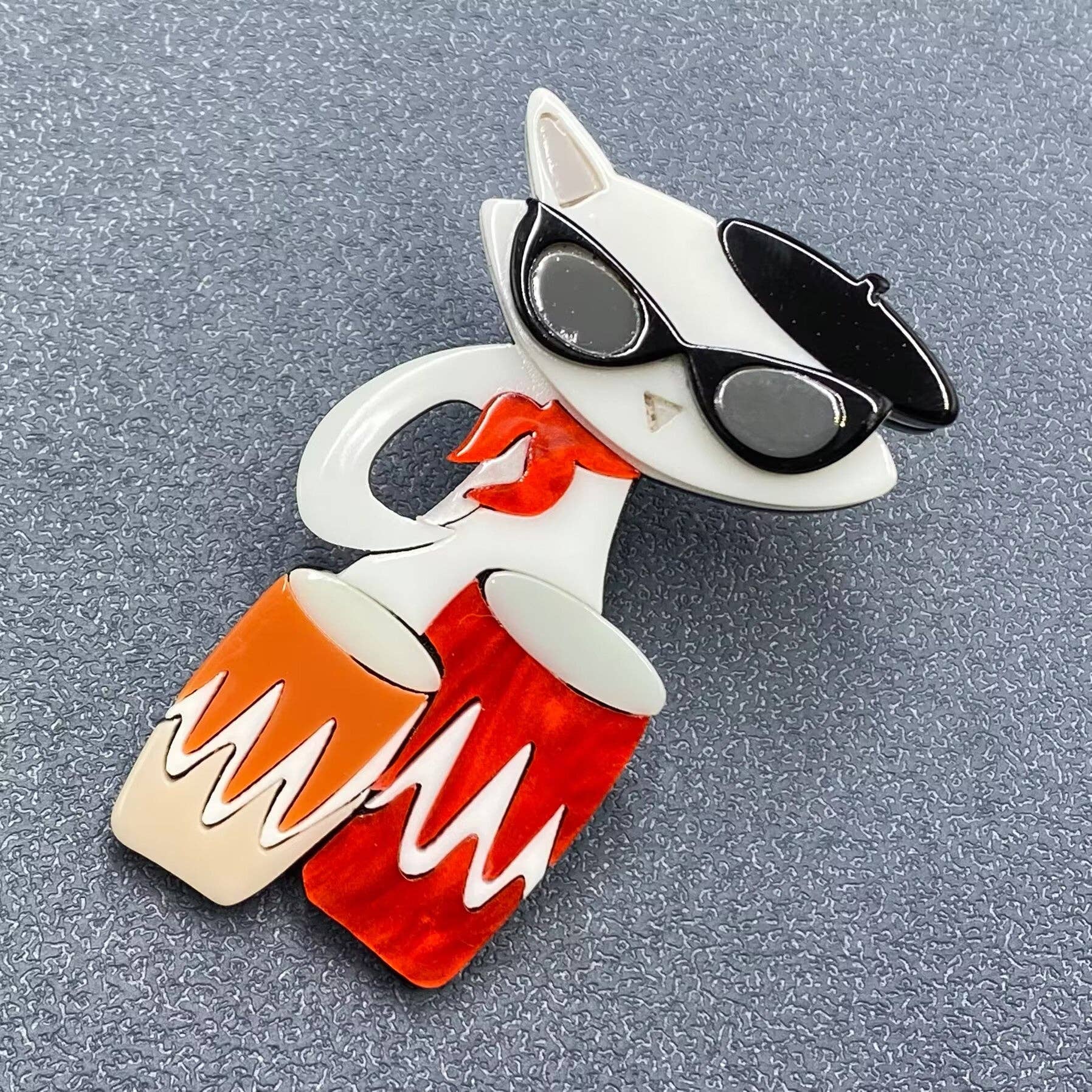 Acrylic cat-shaped brooch with sunglasses and drums on a gray background