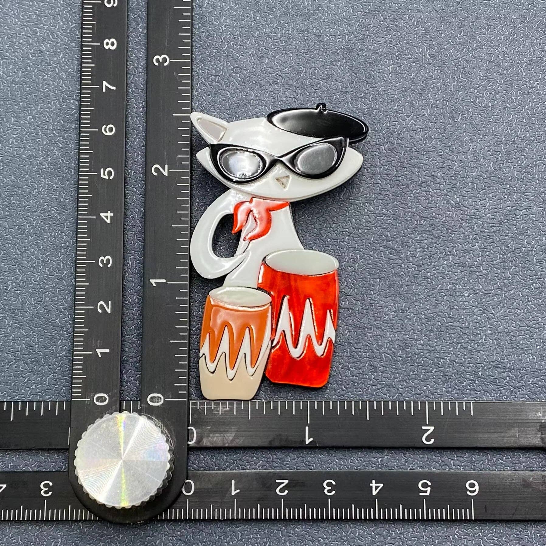 Acrylic cat-shaped brooch with sunglasses and drums on a gray background