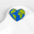 Blue and green heart-shaped earth pin on a white background