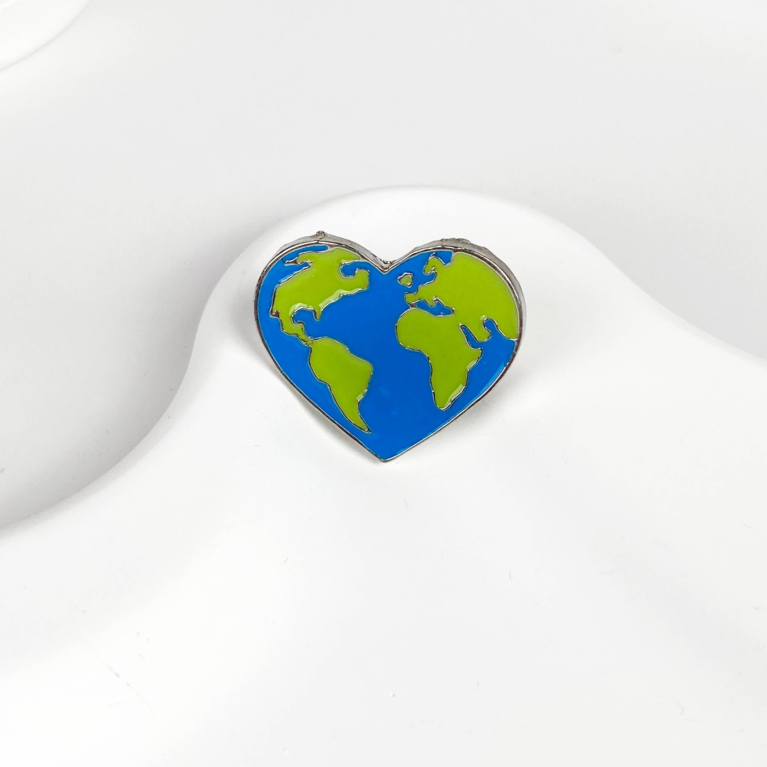 Blue and green heart-shaped earth pin on a white background