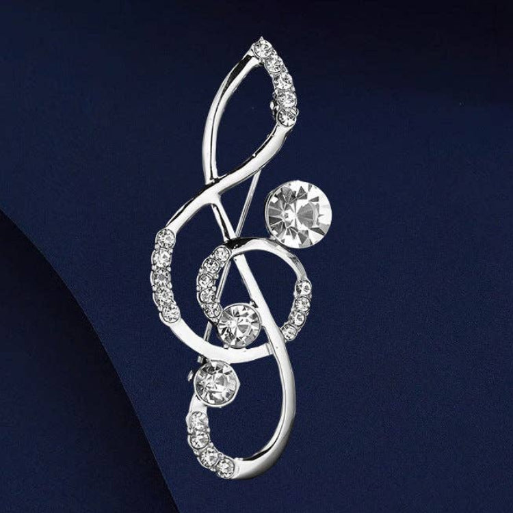 Silver brooch with treble clef design and crystal stone accents on a blue background