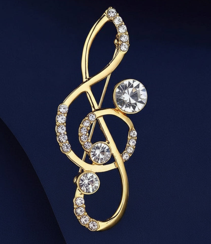 Gold brooch with treble clef design and crystal stone accents on a blue background