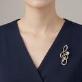 Treble clef design brooch with crystal stone accents pinned on a blue dress