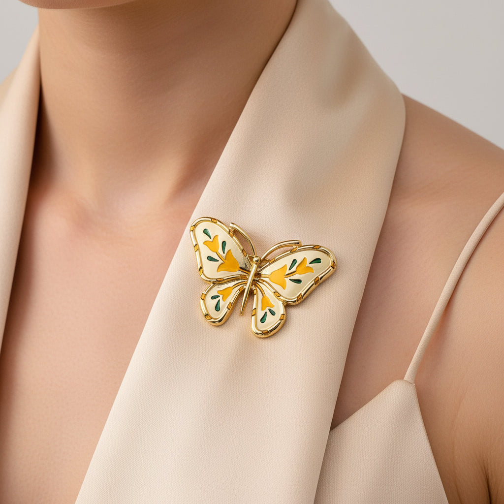 Gold butterfly-shaped brooch with yellow accents on a white scarf