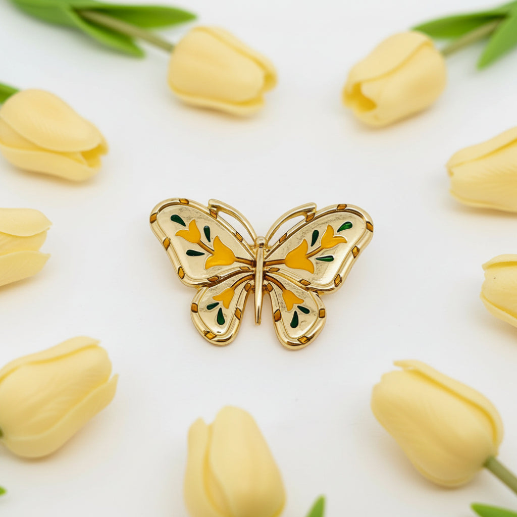 Gold butterfly brooch with yellow and green details on a white background