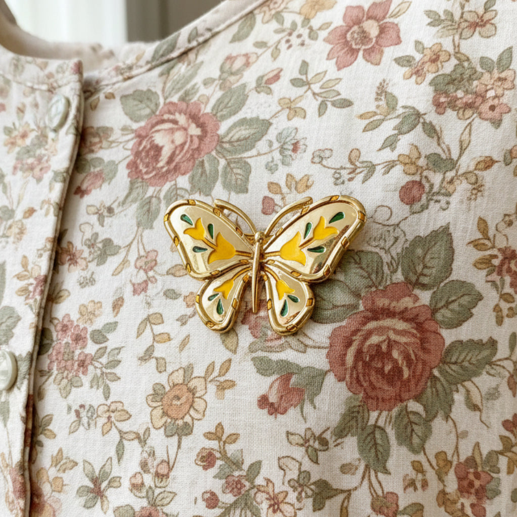Gold butterfly-shaped brooch with yellow accents pinned on a floral dress