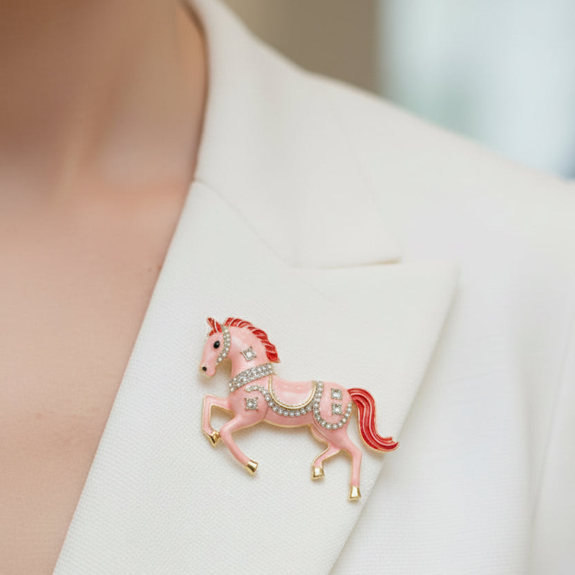 Decorative pink horse brooch with red mane and tail, pinned on a white dress
