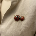 Pair of sheep-shaped brooch pins on a textured beige background