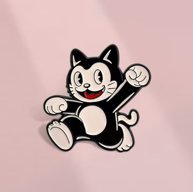 Black and white cat-shaped lapel pin on a pastel pink background