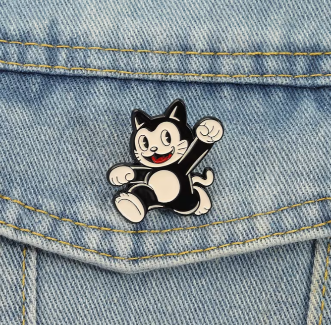 Black and white cat-shaped lapel pin on a denim surface