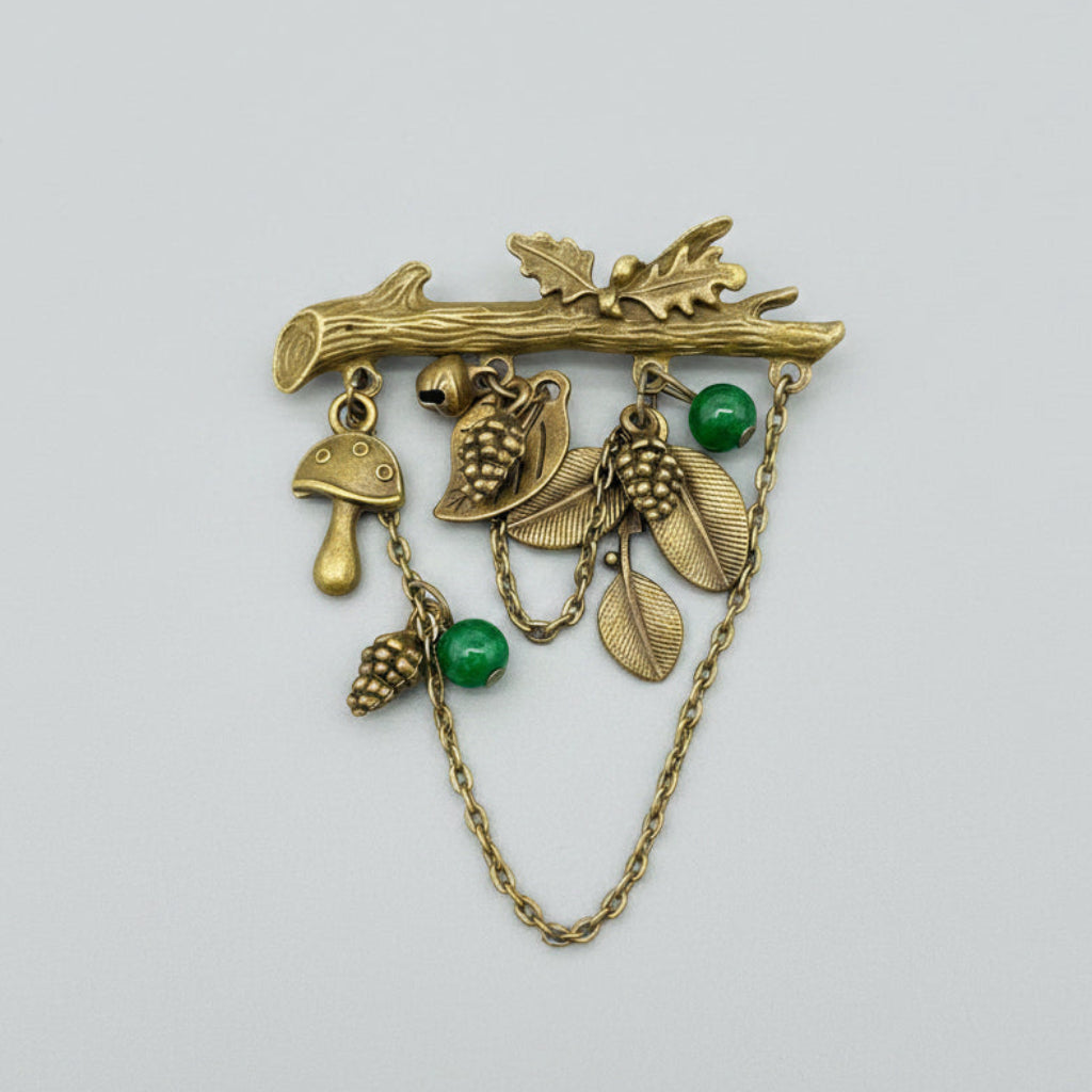 Bronze brooch with nature-themed charms on a gray background