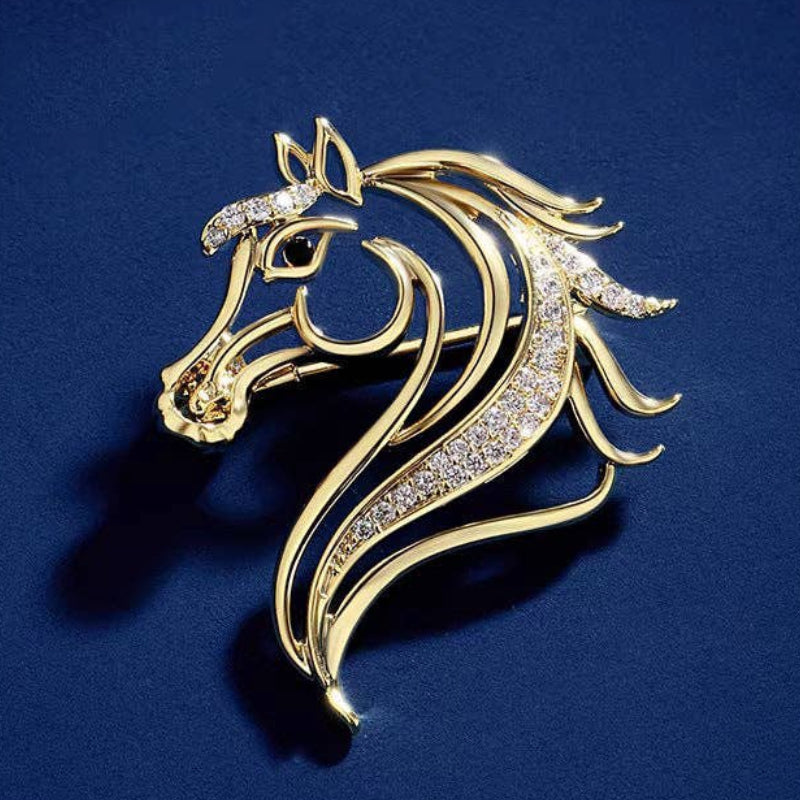 Gold horse head silhouette brooch with gemstones on a blue background
