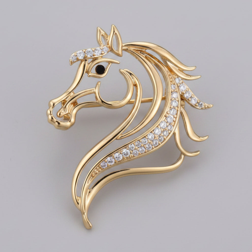 Gold horse head silhouette brooch with gemstones on a gray background