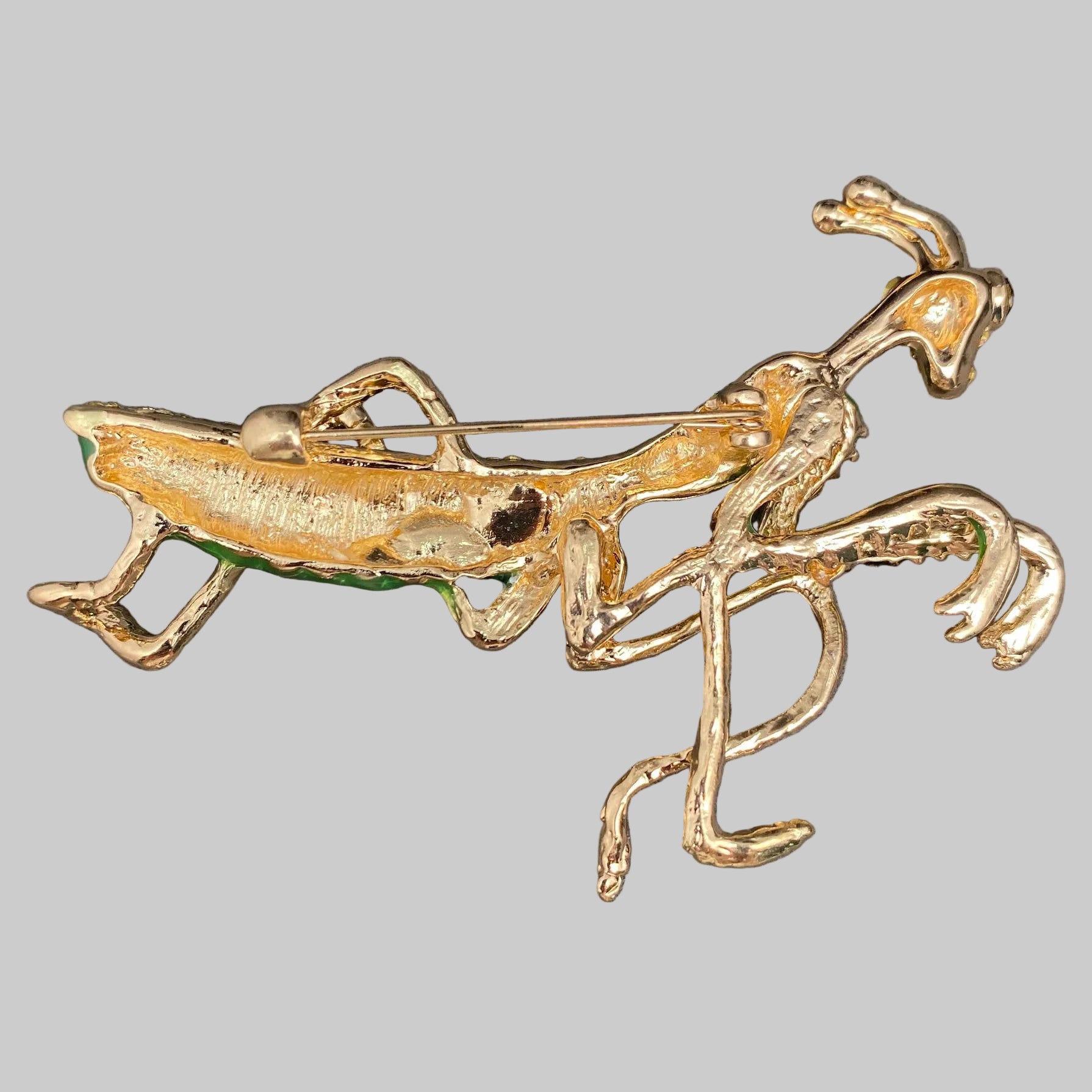 Back view of decorative mantis brooch with green and gold details, showing the clasp mechanism