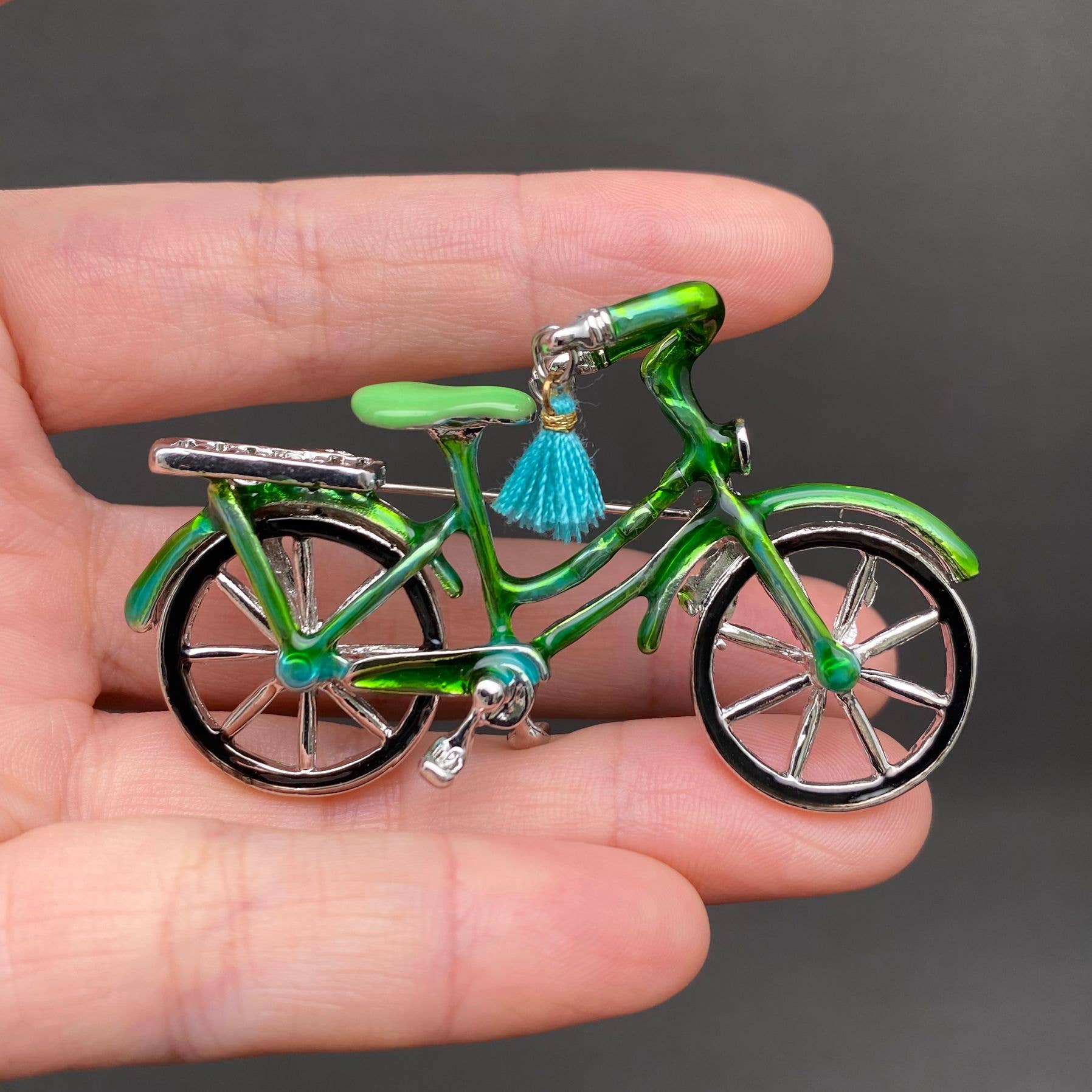 Green enamel bicycle-shaped brooch with blue tassel handle bars