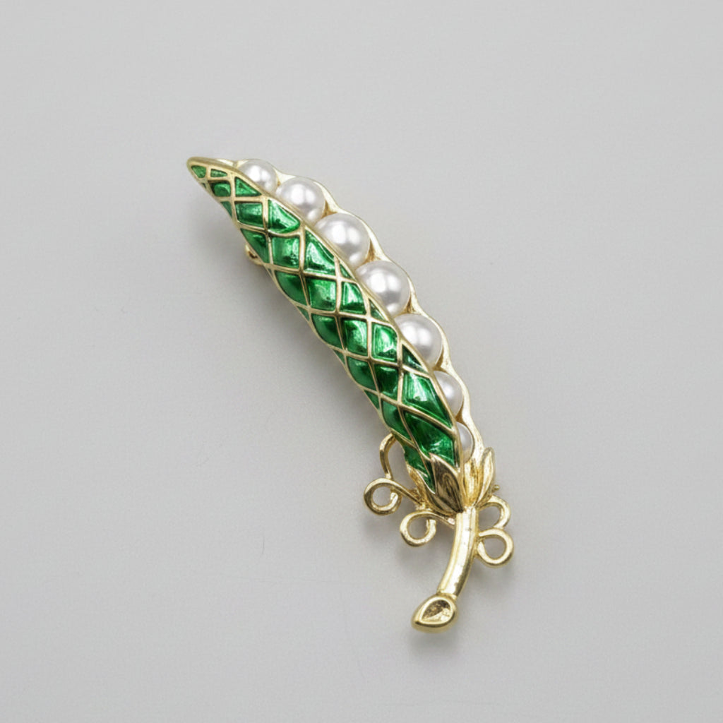 Green enamel pearl pea pod brooch on a gray background
