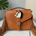White acrylic horse head brooch with black mane, pinned on a brown hand bag