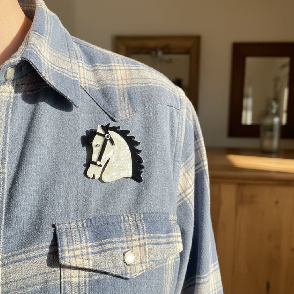 White acrylic horse head brooch with black mane pinned on a denim shirt