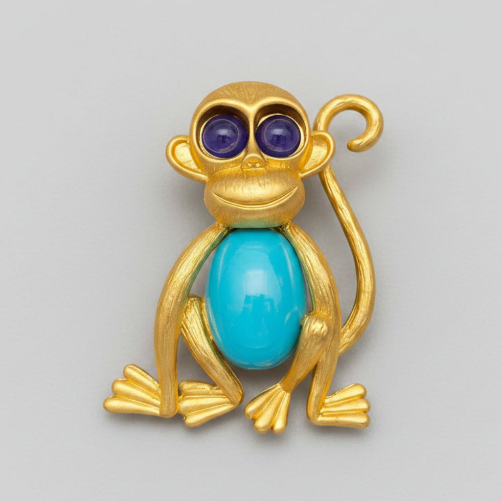 Jelly belly golden monkey brooch with blue stone belly and purple eyes,  on a gray background