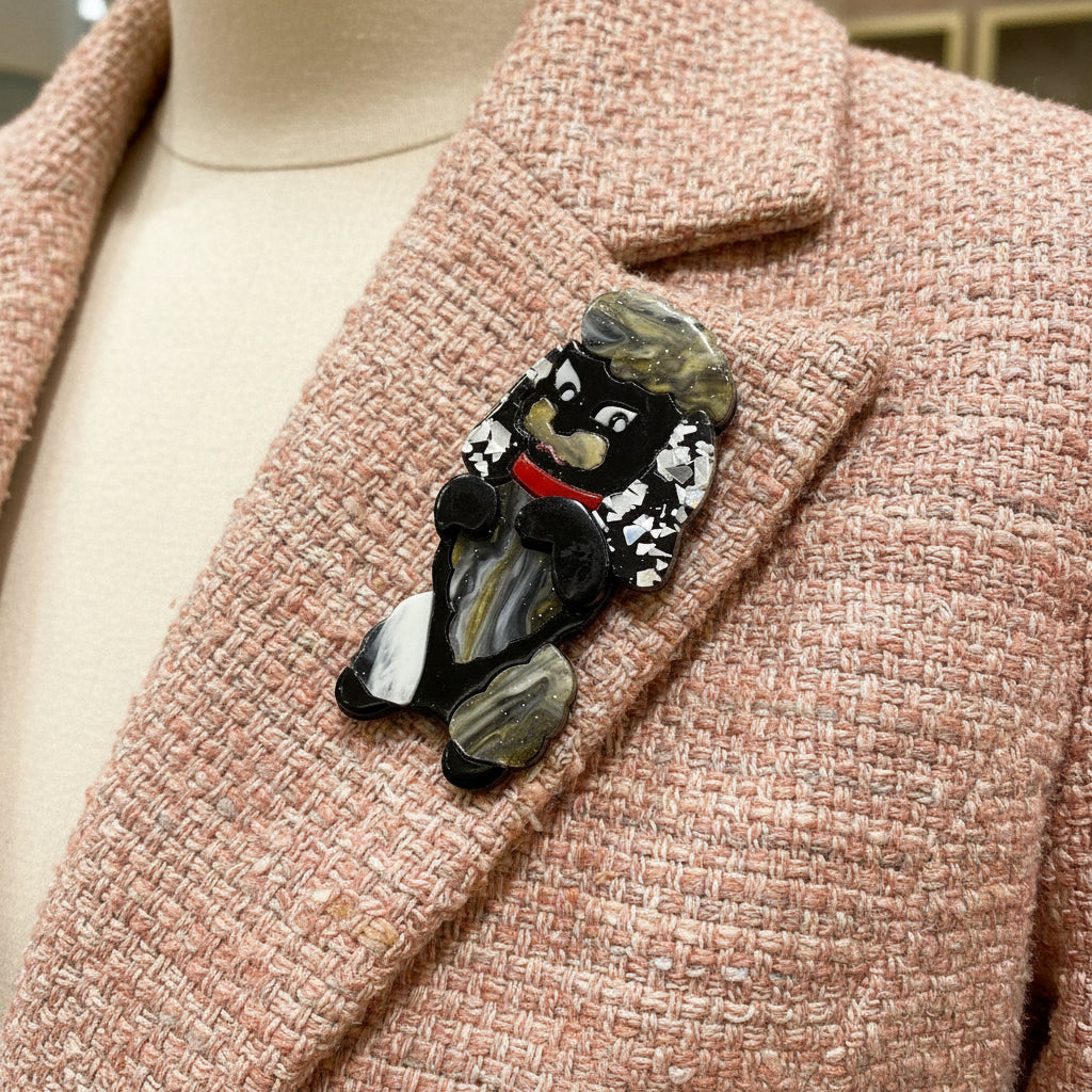 Dog-shaped brooch with black, white, and red colors on a pastel jacket
