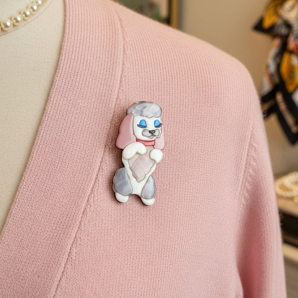 Dog-shaped brooch with pink, white, and red colors pinned on a pink sweater
