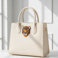 Leopard head design brooch pinned on a white handbag with a light background