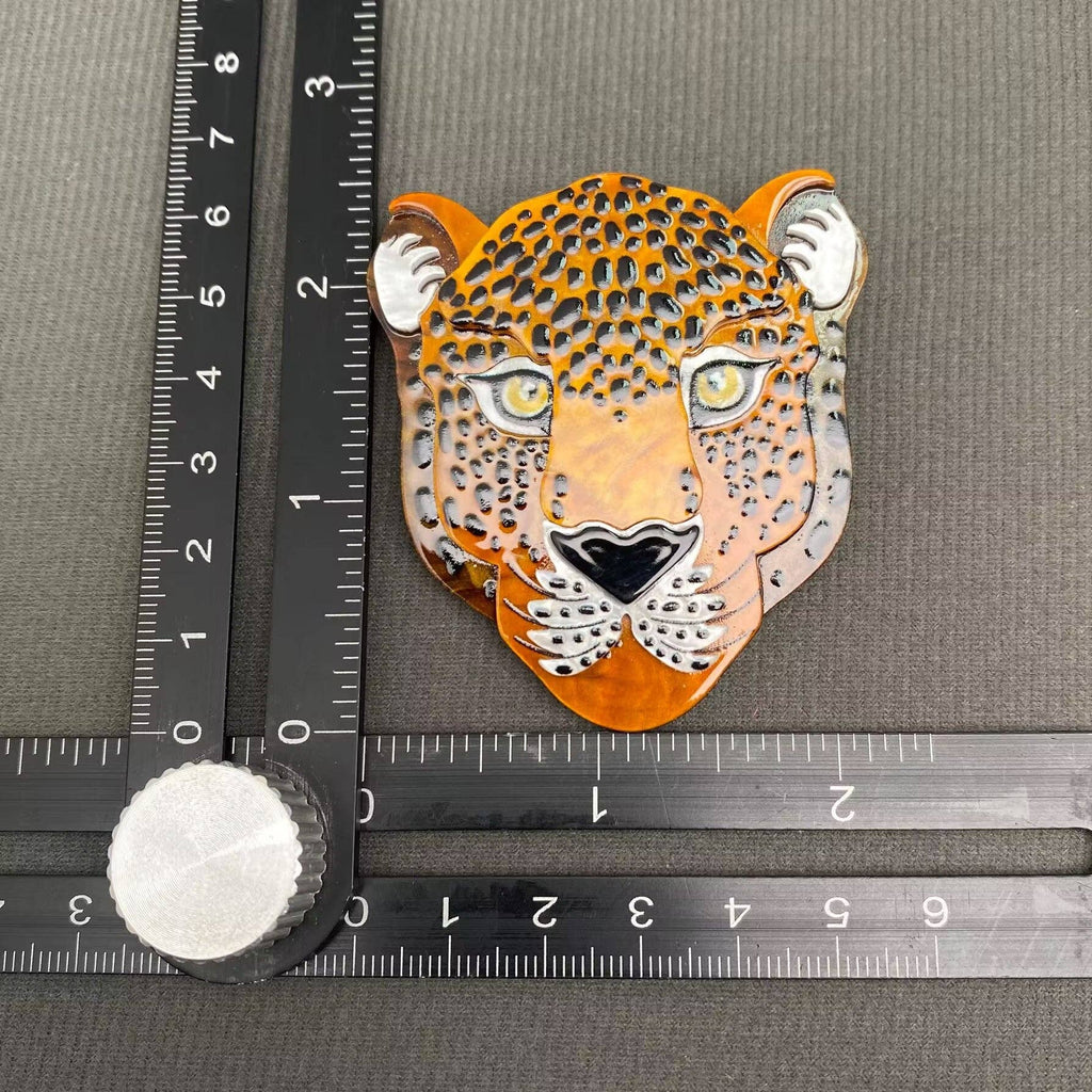 Leopard head design brooch on a gray background with a ruler for scale