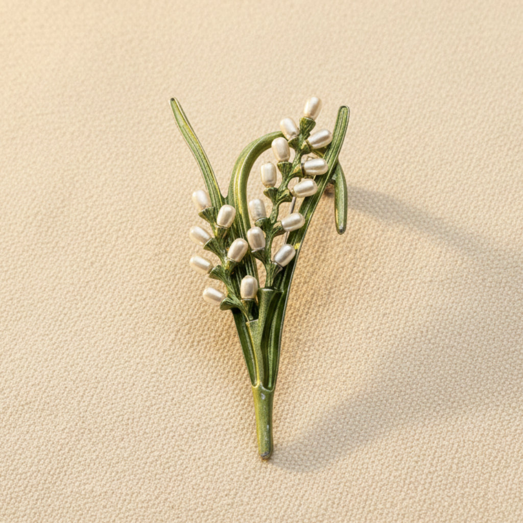 Green enamel rice plant brooch with pearl accents on a beige background