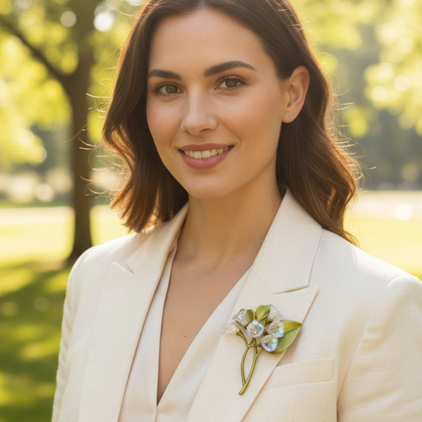 Floral brooch with green leaves and silver flowers, pinned on a woman's white suite