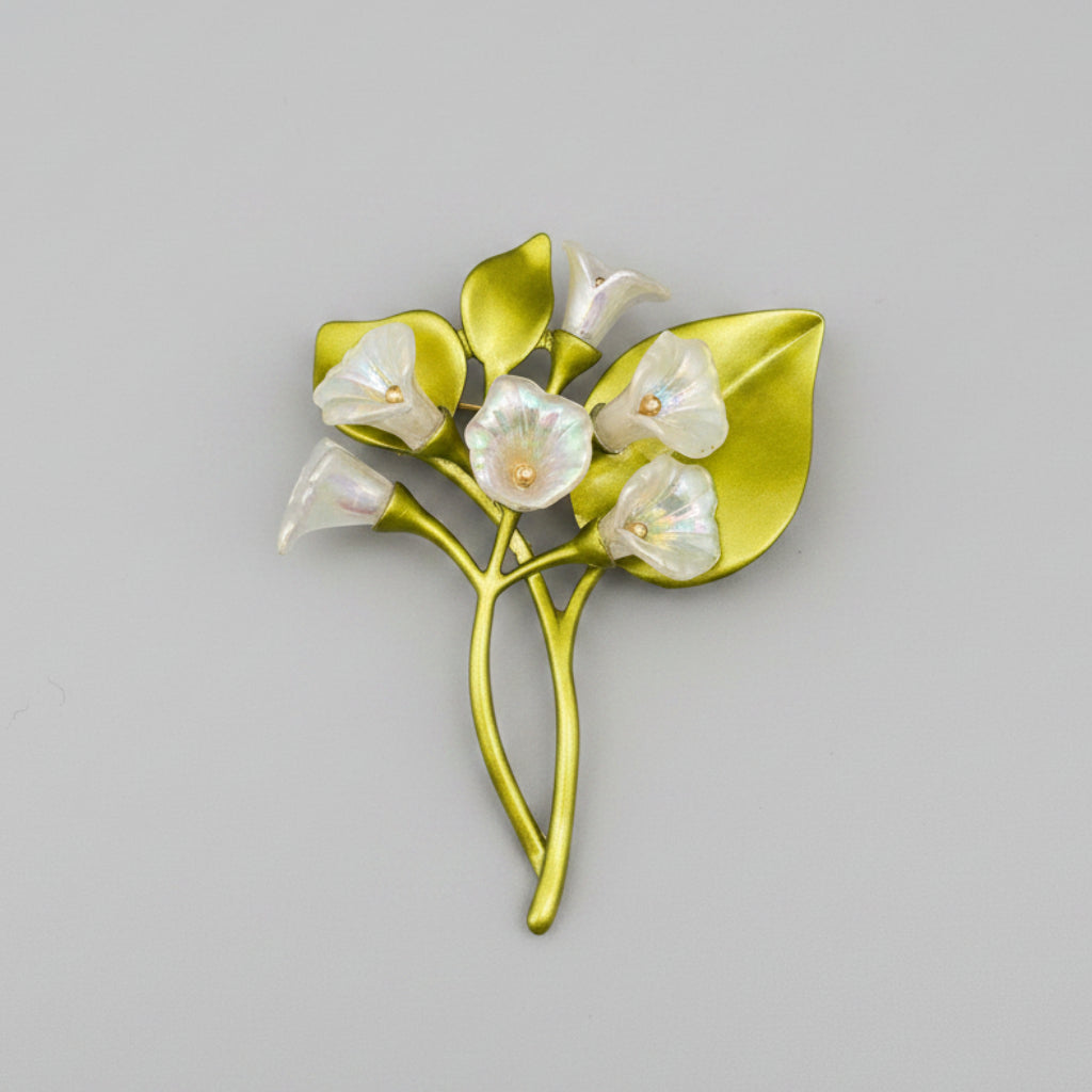 Floral brooch with green leaves and silver flowers on a gray background